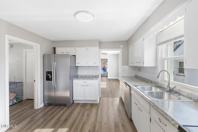 kitchen with stainless steel appliances, backsplash, white cabinetry, and sink