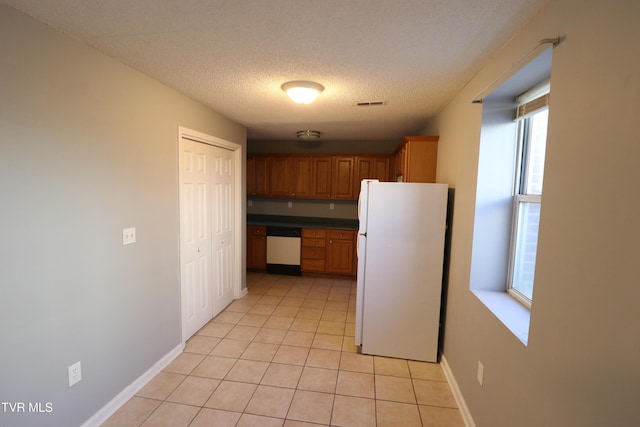 kitchen with a textured ceiling, light tile patterned floors, and white appliances