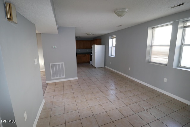 empty room with light tile patterned floors and a textured ceiling