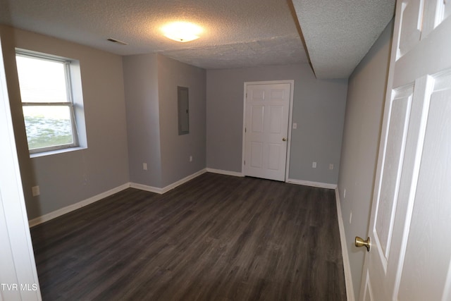 spare room with a textured ceiling, dark hardwood / wood-style flooring, and electric panel