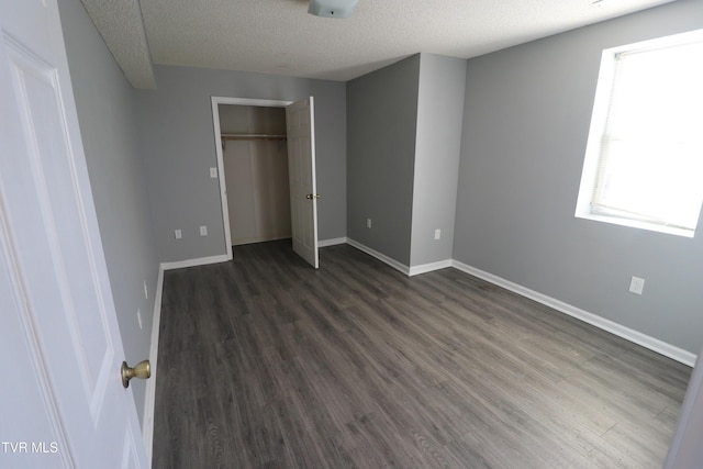 unfurnished bedroom featuring a textured ceiling, a closet, and multiple windows