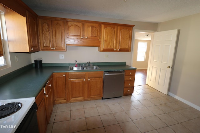 kitchen with sink, dishwasher, light tile patterned flooring, and a textured ceiling