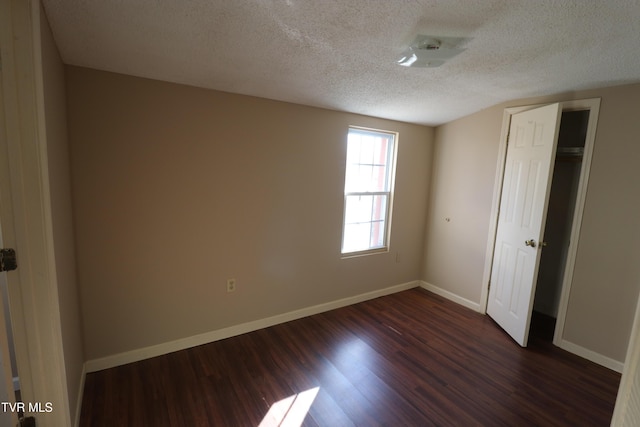 unfurnished bedroom with a textured ceiling, a closet, and dark hardwood / wood-style floors