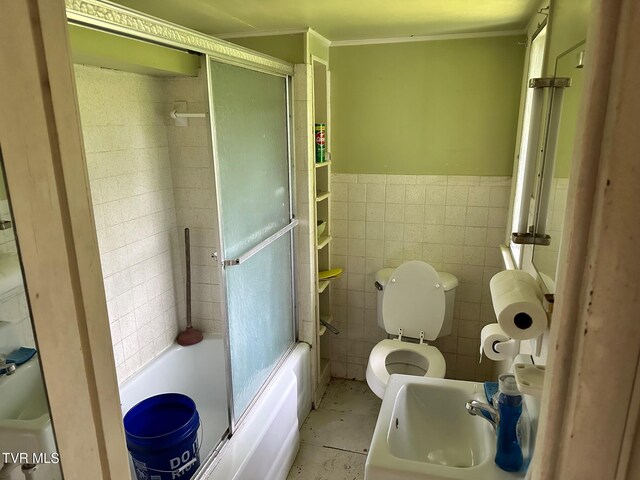 full bathroom featuring sink, tile walls, bath / shower combo with glass door, tile patterned floors, and toilet