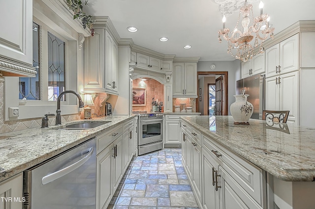 kitchen with appliances with stainless steel finishes, a notable chandelier, decorative light fixtures, light stone countertops, and sink