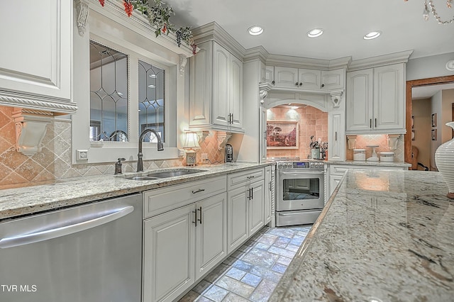 kitchen with white cabinets, stainless steel appliances, decorative backsplash, sink, and light stone counters