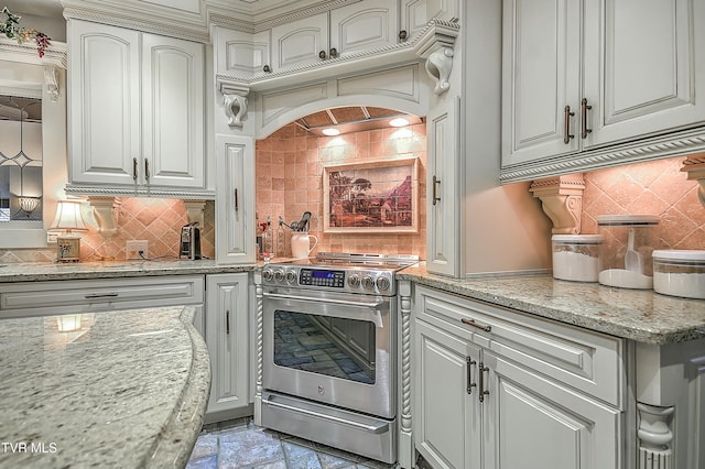 kitchen featuring tasteful backsplash, stainless steel electric range oven, light stone counters, and custom exhaust hood