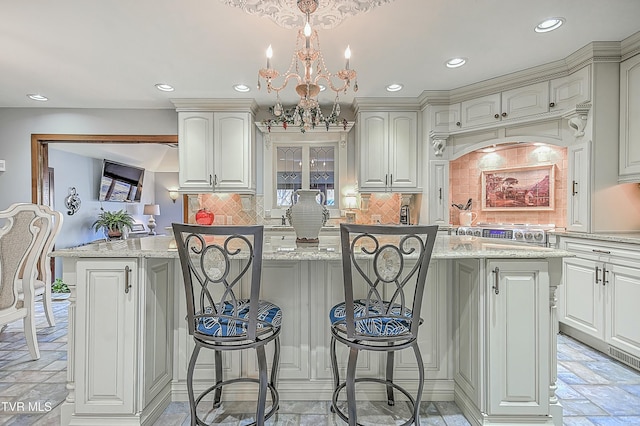 kitchen with a breakfast bar area, pendant lighting, light stone counters, and a center island