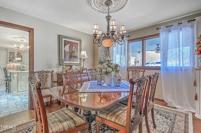 dining room with wood-type flooring, a textured ceiling, and a notable chandelier