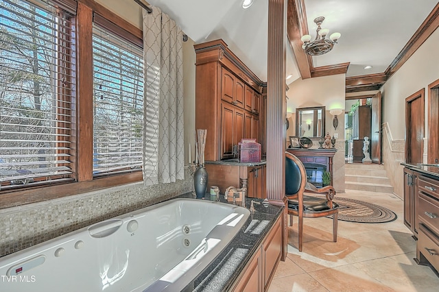 bathroom with tiled bath, plenty of natural light, an inviting chandelier, and tile patterned flooring