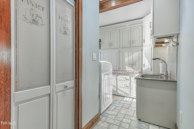 interior space featuring white cabinetry, sink, dishwashing machine, and washer / clothes dryer