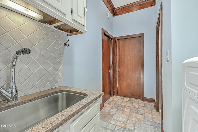 kitchen featuring white cabinets, washer / clothes dryer, sink, and ornamental molding