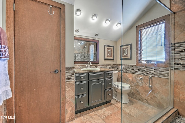 bathroom with vanity, tile walls, toilet, vaulted ceiling, and a tile shower