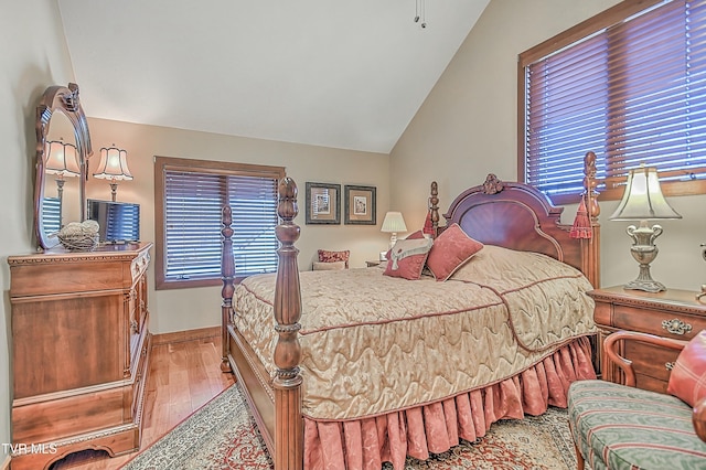 bedroom with lofted ceiling, light hardwood / wood-style floors, and multiple windows