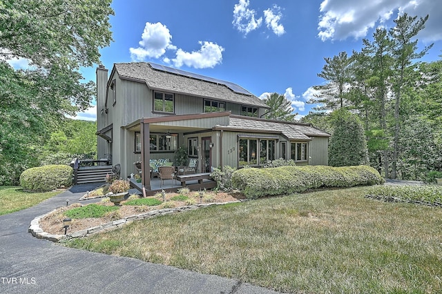 view of front of house featuring a front lawn, covered porch, and solar panels