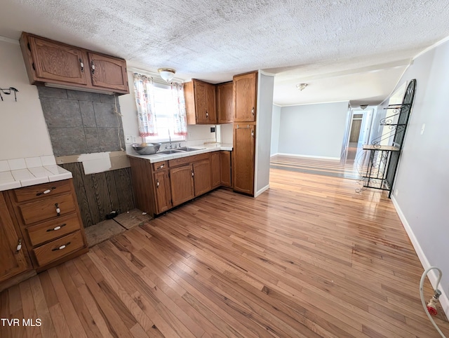 kitchen featuring sink, a textured ceiling, and light hardwood / wood-style flooring