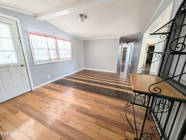 foyer featuring vaulted ceiling with beams, wood-type flooring, a textured ceiling, and ornamental molding