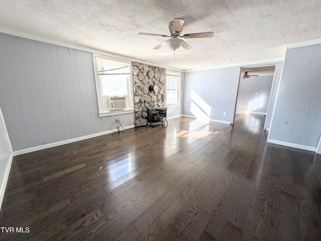 unfurnished living room with a textured ceiling, cooling unit, dark hardwood / wood-style flooring, a wood stove, and wood walls