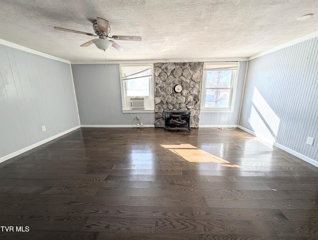 unfurnished living room featuring a stone fireplace, ceiling fan, dark wood-type flooring, a textured ceiling, and ornamental molding