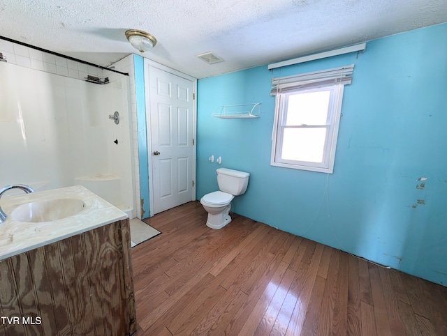 bathroom with toilet, a shower, wood-type flooring, a textured ceiling, and vanity