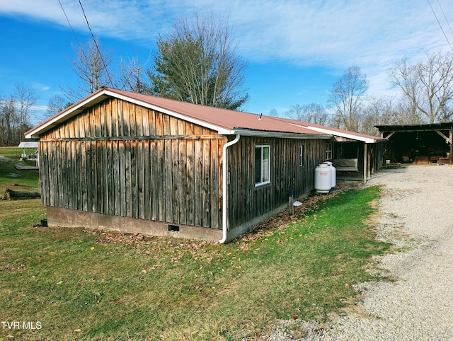 view of side of property with a carport, an outbuilding, and a lawn