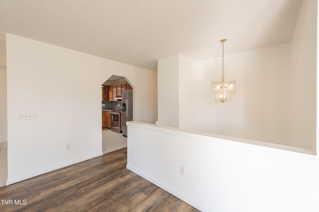 unfurnished room featuring a notable chandelier and dark hardwood / wood-style flooring