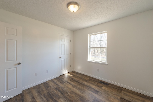 unfurnished room with dark wood-type flooring and a textured ceiling