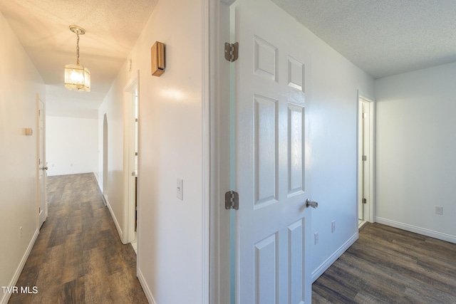 corridor with dark hardwood / wood-style floors and a textured ceiling