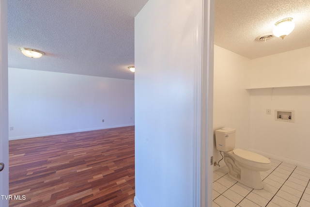 bathroom with wood-type flooring, toilet, and a textured ceiling