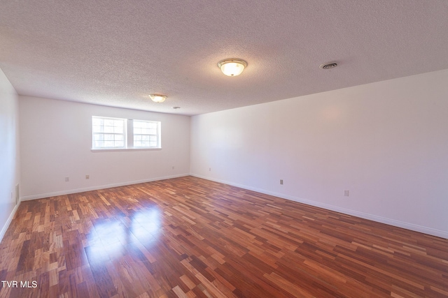 empty room with a textured ceiling and dark hardwood / wood-style flooring