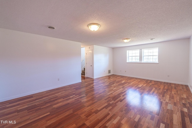 spare room with a textured ceiling and dark wood-type flooring