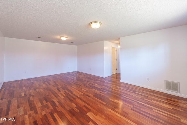 spare room featuring dark hardwood / wood-style flooring and a textured ceiling