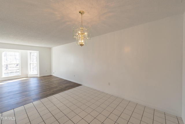 empty room with a textured ceiling and an inviting chandelier