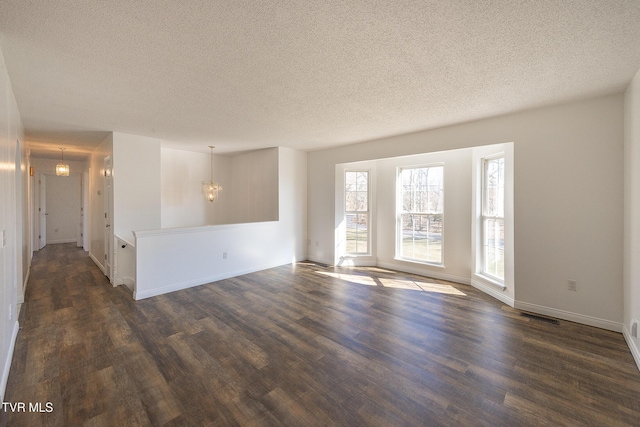 spare room with dark wood-type flooring, a chandelier, and a textured ceiling