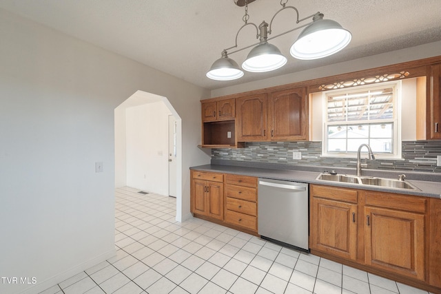 kitchen featuring decorative light fixtures, backsplash, stainless steel dishwasher, sink, and a textured ceiling