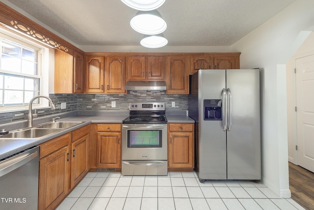 kitchen with light tile patterned floors, ventilation hood, appliances with stainless steel finishes, decorative backsplash, and sink