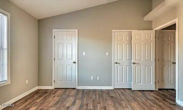 unfurnished bedroom featuring lofted ceiling and dark hardwood / wood-style floors