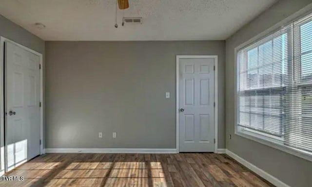 interior space with ceiling fan, a textured ceiling, and dark hardwood / wood-style floors