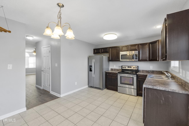 kitchen with stainless steel appliances, hanging light fixtures, ceiling fan with notable chandelier, dark brown cabinetry, and sink