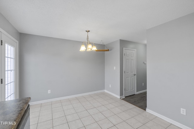 spare room featuring a textured ceiling, light tile patterned floors, and an inviting chandelier