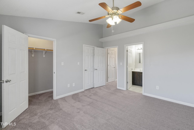 unfurnished bedroom with ceiling fan, ensuite bathroom, light carpet, and vaulted ceiling