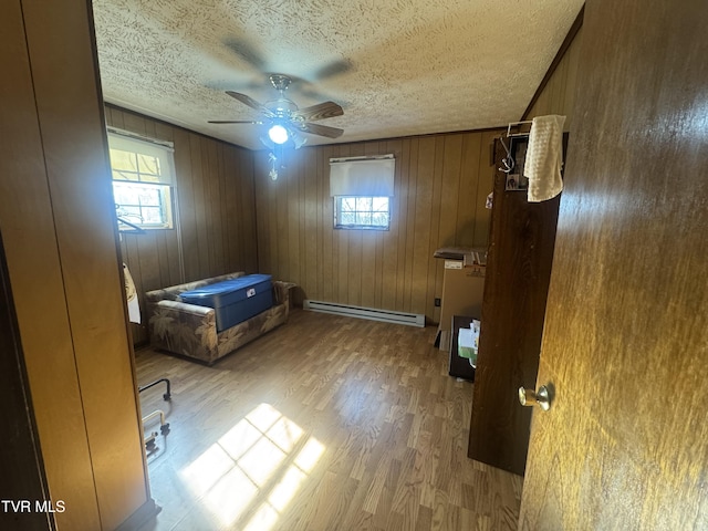 unfurnished bedroom with multiple windows, wood walls, a textured ceiling, and baseboard heating