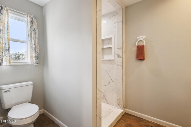 bathroom with hardwood / wood-style floors, tiled shower, and toilet