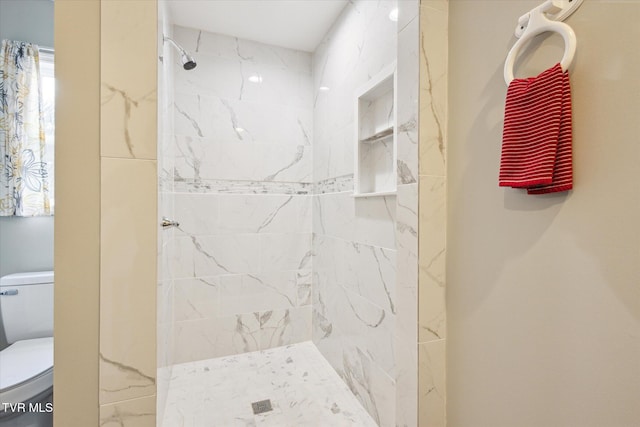 bathroom with tiled shower and toilet