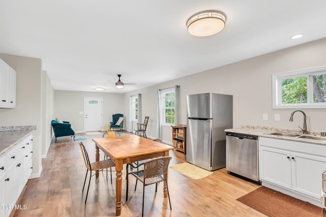 dining room featuring ceiling fan, sink, and light hardwood / wood-style flooring