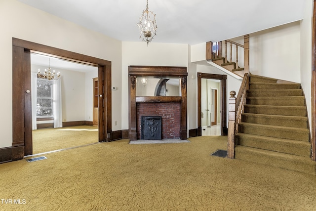 unfurnished living room with carpet floors, a notable chandelier, and a brick fireplace