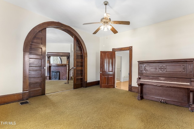 interior space featuring light carpet, ceiling fan, and a fireplace