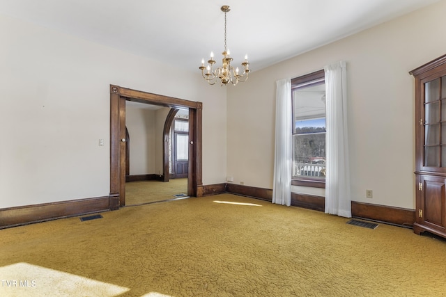 carpeted spare room with a chandelier