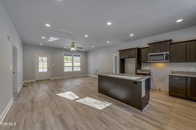 kitchen featuring light stone counters, dark brown cabinetry, and light wood-type flooring