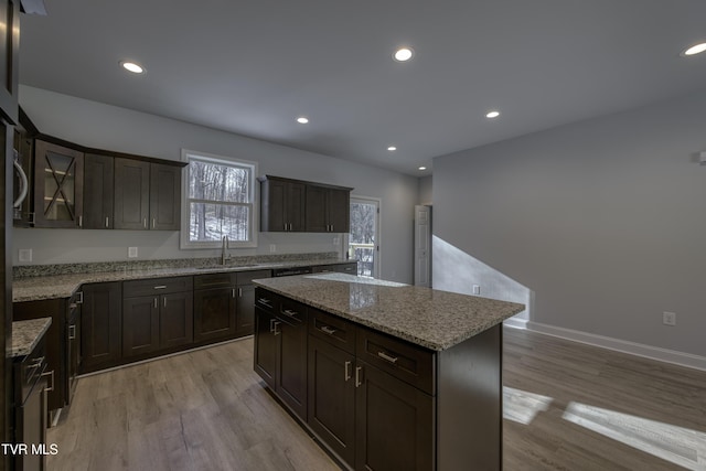 kitchen featuring a center island, sink, dark brown cabinets, and light wood-type flooring